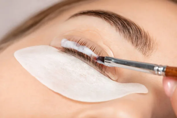 Wimpernlifting mit Pinsel am Auge einer Klientin